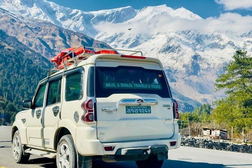 Un SUV blanco con una bandera roja en la parte superior, estacionado frente a montañas nevadas. 3