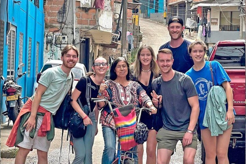 Un gruppo di persone in strada, con un edificio blu e un camion rosso sullo sfondo. 1