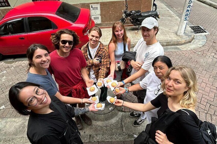 Eine Gruppe von Personen hält Donuts und es steht ein rotes Auto in einer Stadtumgebung. 5