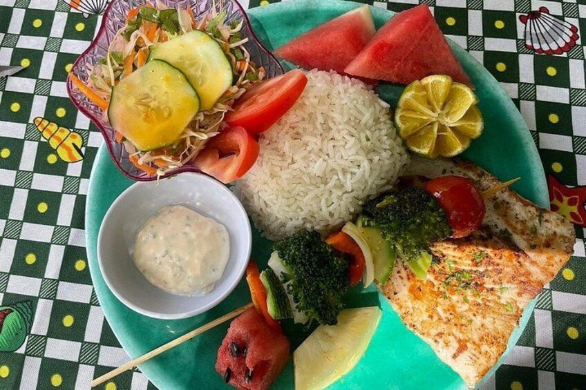 Une assiette contenant du riz, des légumes, une tranche de poisson et un morceau de pain. 5