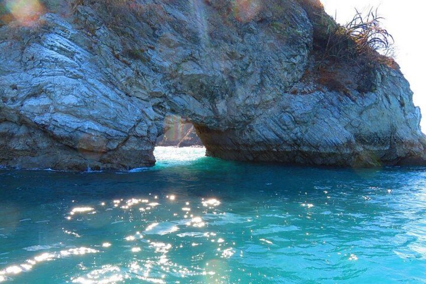 Un paysage côtier rocheux, avec une grande formation rocheuse et une mer d’un bleu limpide. 4