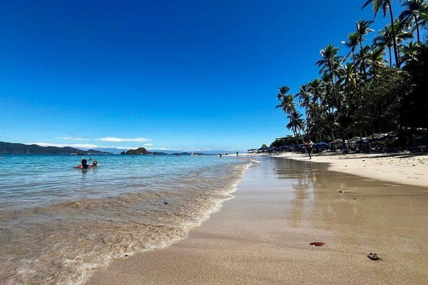 Une plage avec une eau d’un bleu limpide, des palmiers et une rive sablonneuse. 3