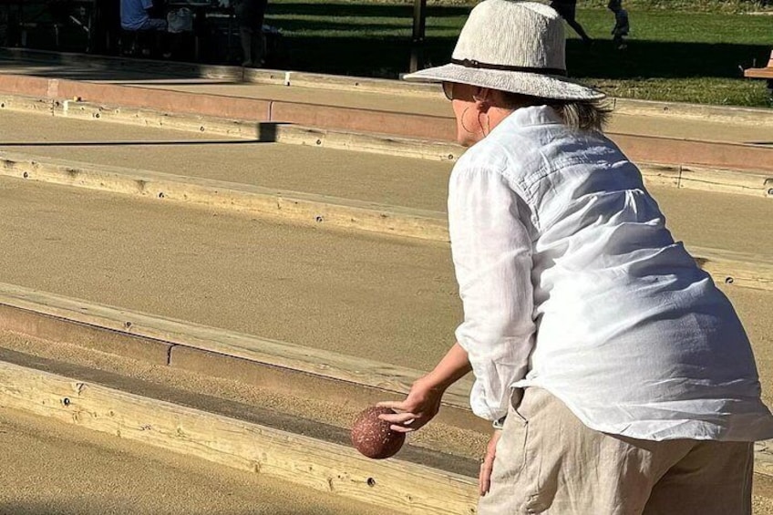 Une personne jouant à la pétanque sur un terrain verdoyant. 3