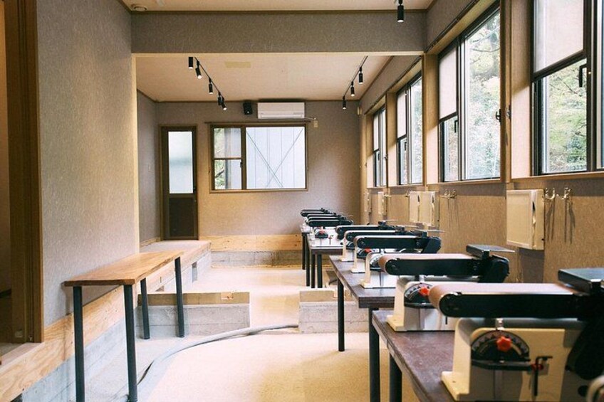 Un aula con mesas largas y sillas, ventanas amplias y una puerta. 2