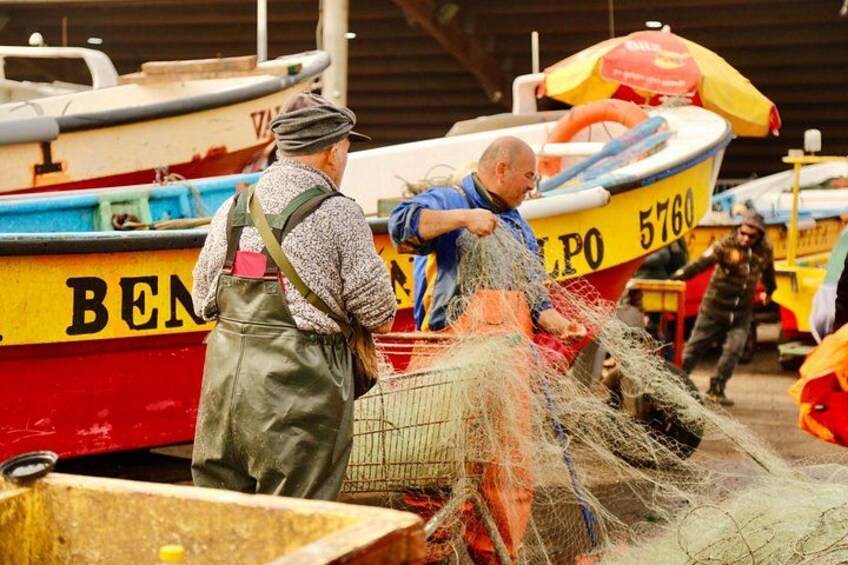 Two men handling fishing nets near a boat with the number 5760. 4