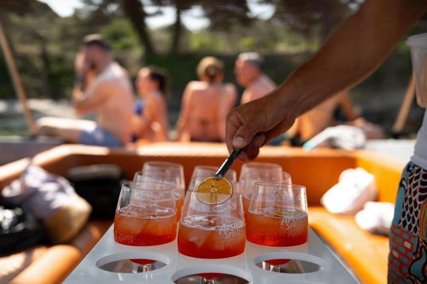 A person pouring a drink into a glass with a lemon slice. There are multiple glasses on a tray. 3
