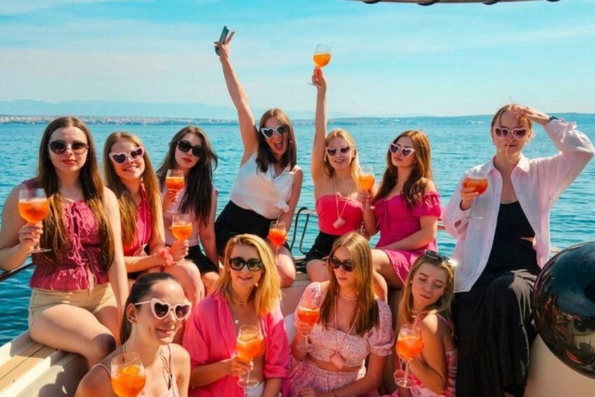 A group of people on a boat with drinks, water, and a clear sky. 1