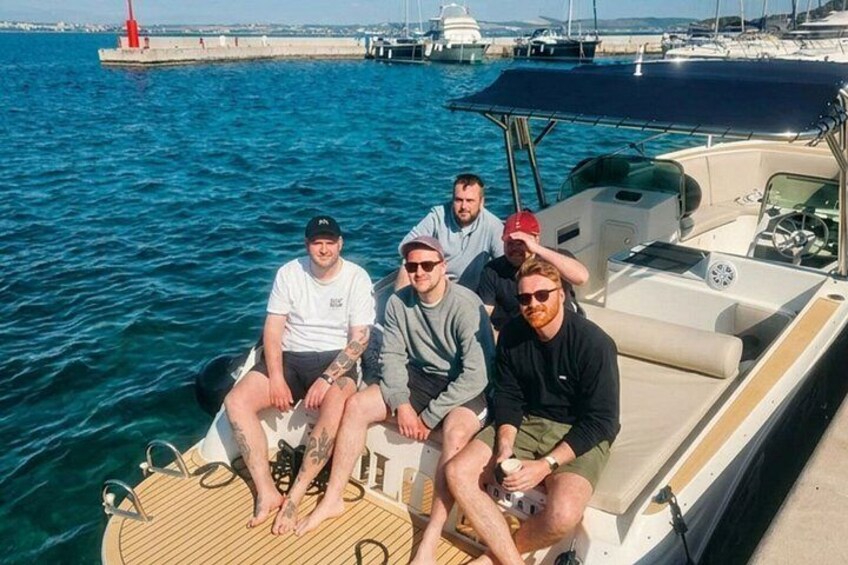 A group of people on a boat in a harbor with a lighthouse in the background. 2