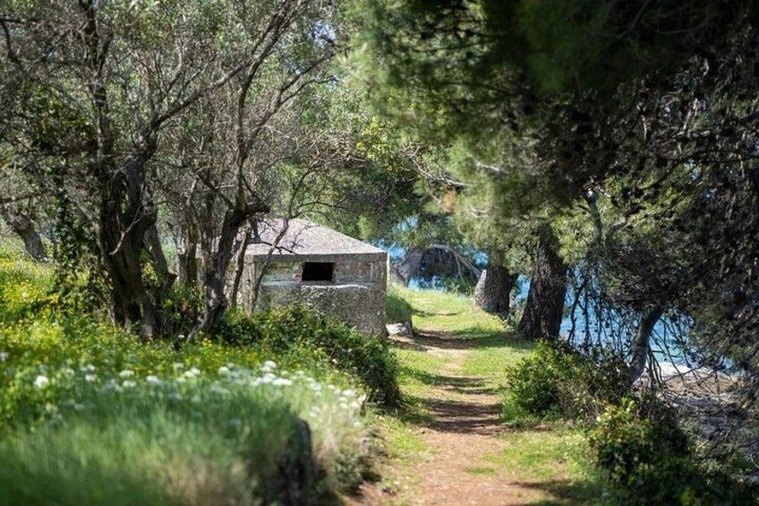 A stone building surrounded by trees and a path leading to a body of water. 4