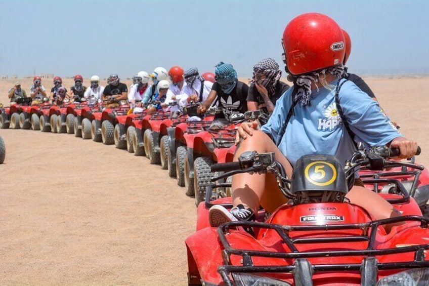 A group of people riding ATVs in a line on a dirt road in a desert. 4
