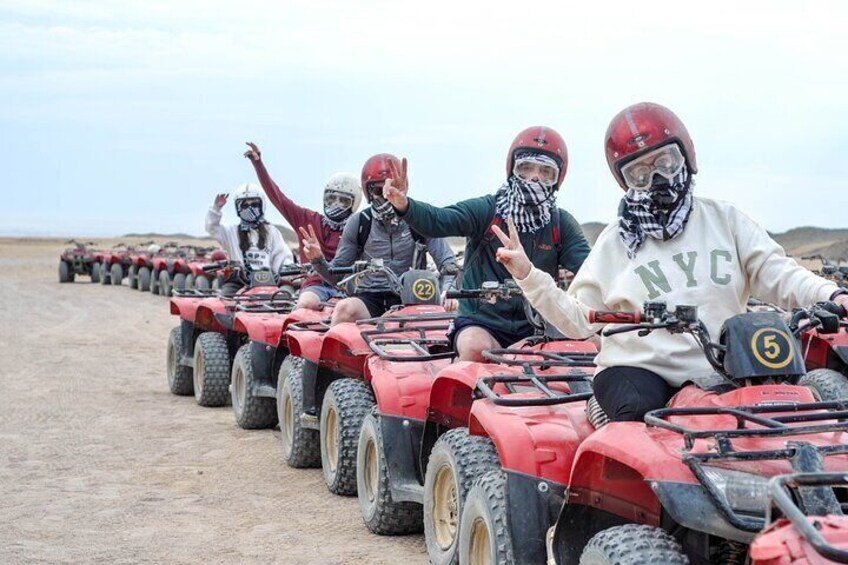 A group of people riding ATVs on a dirt road in a desert landscape. 3