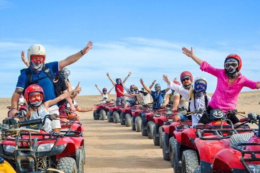 People riding ATVs on a dirt road in a desert landscape. 1