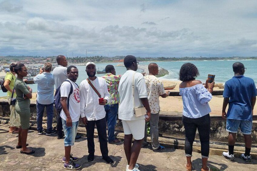 Un grupo de personas en una plataforma de piedra con vistas a la costa, el mar y tierra distante. 3