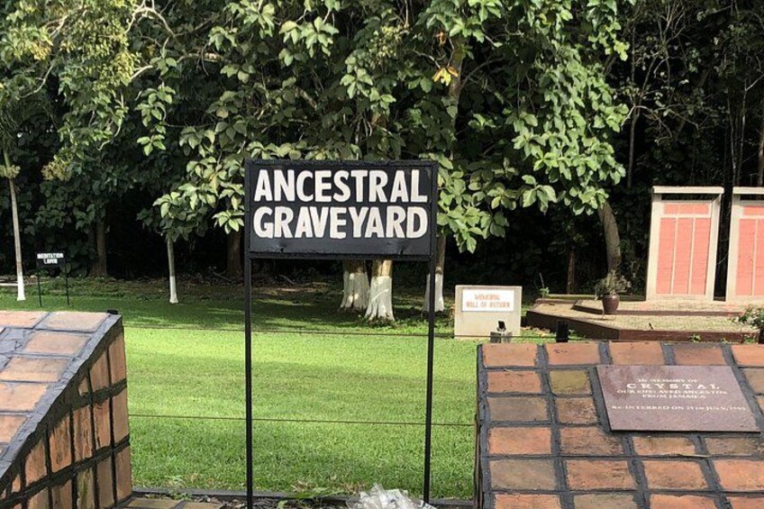 Un letrero de cementerio ancestral, un muro de ladrillo y una zona arbolada con césped. 5