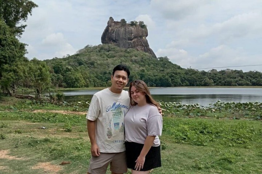 A couple standing in front of a large rock formation with a lake in the background. 4