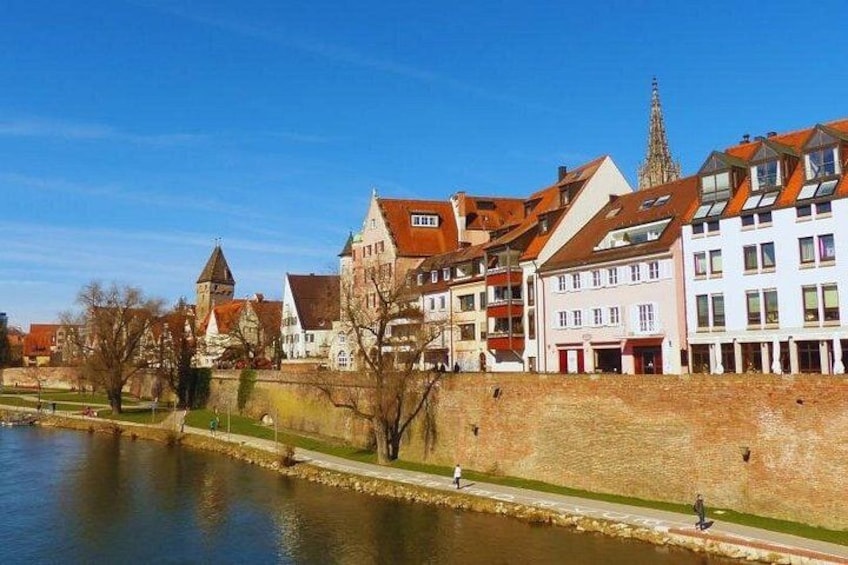 A riverside town with historic buildings, a bridge, and a church spire. 2