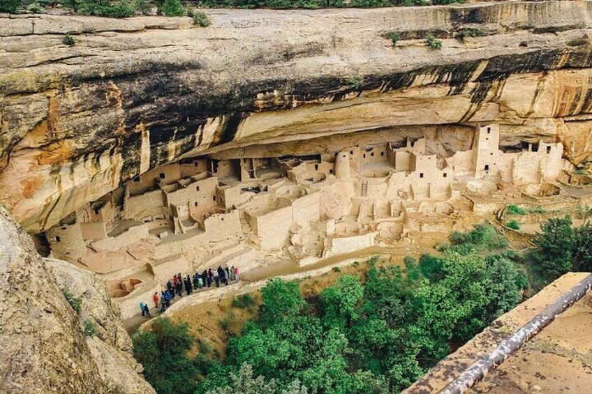 Ancient cliff dwellings with a group of people observing. 2