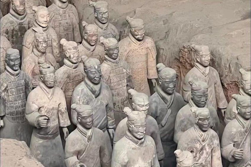 A collection of terracotta soldiers in various poses, lined up in a formation. 4