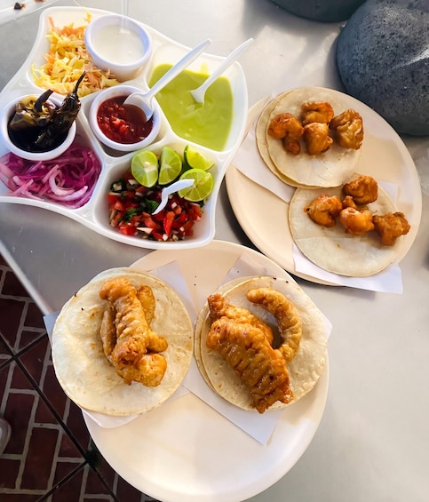 Un repas composé de tacos, de salade de chou et de différentes sauces. 3