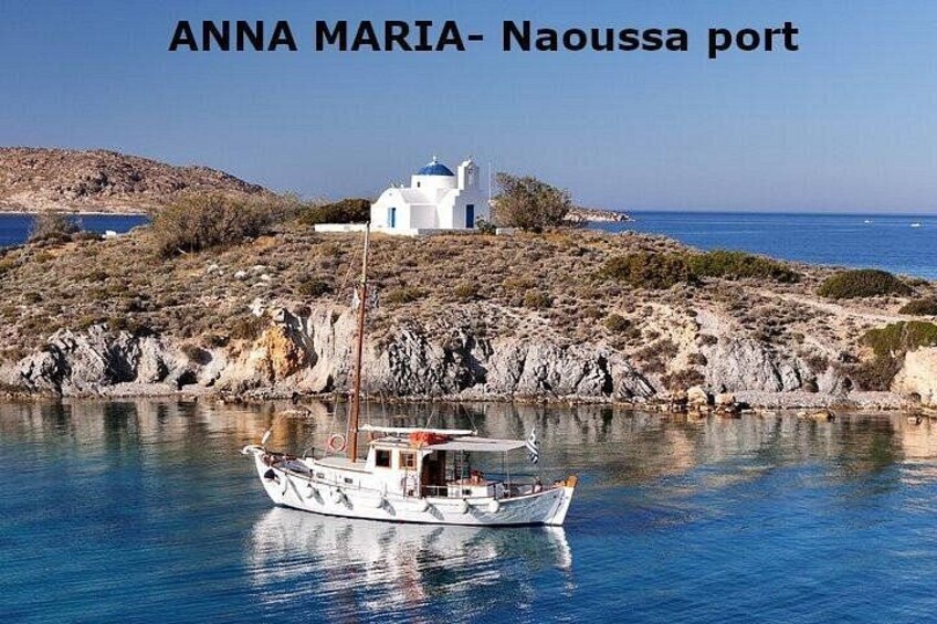 A boat near a white church on a rocky island with clear blue water. 1