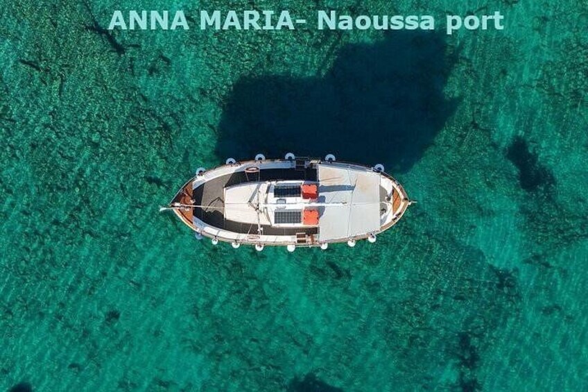 A boat anchored in clear turquoise waters at Naoussa port. 2
