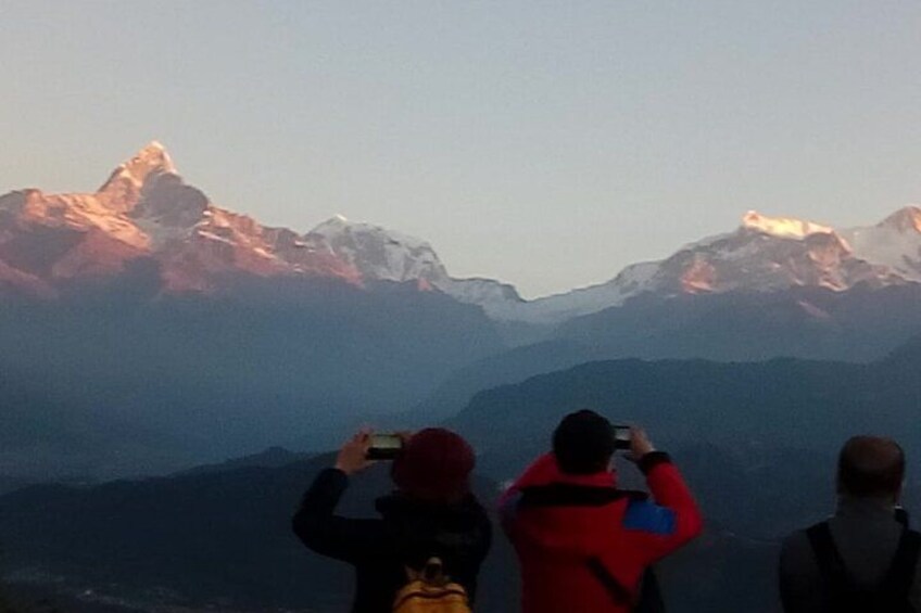 A group of people taking photographs of a mountain range. 1