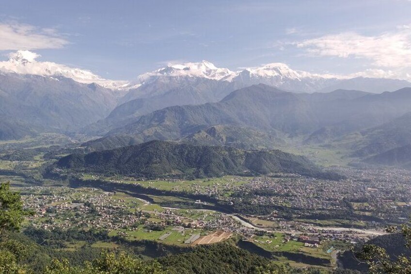 A mountainous landscape with a valley, a town, and snow-capped peaks. 4