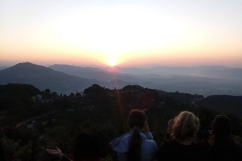 A sunset over a mountainous landscape with a group of people observing the view. 3