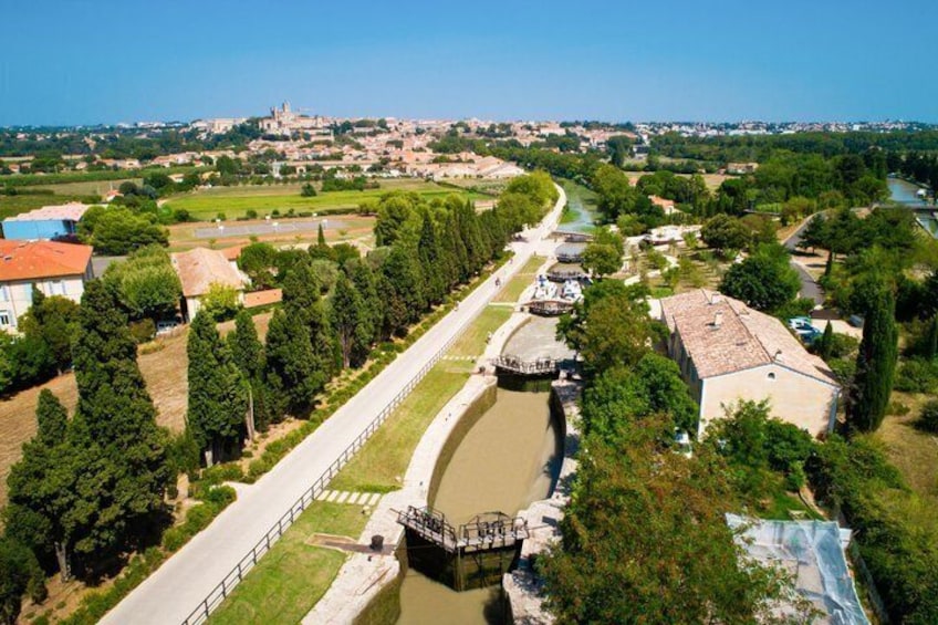 A river with a bridge, a town in the background, and a large building with a red roof. 4