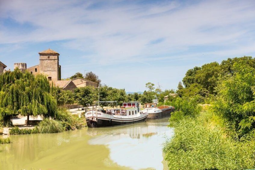 A river with boats, a castle-like structure, and lush greenery. 1