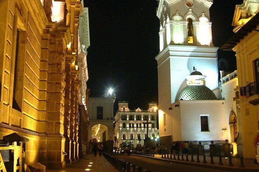 A nighttime street with illuminated buildings and a prominent dome structure. 5