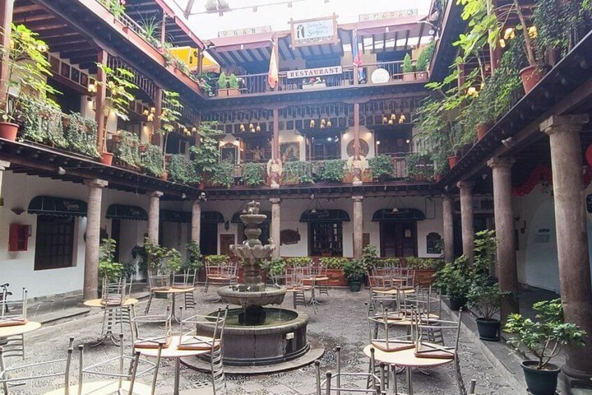 A courtyard with a fountain, potted plants, and outdoor seating. 1