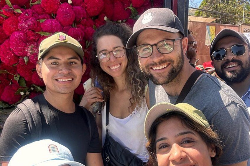 Un grupo de personas posando frente a un fondo de flores rojas. 2