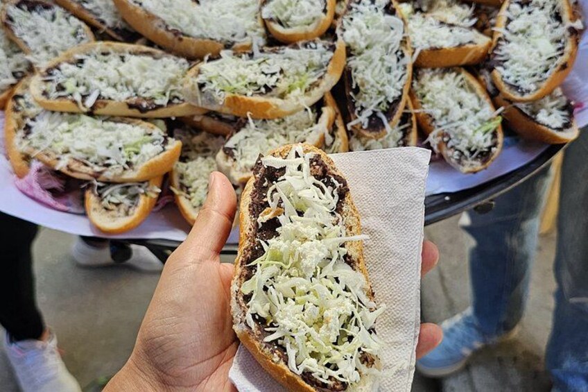 Una persona sosteniendo un sándwich con queso desmenuzado. 5