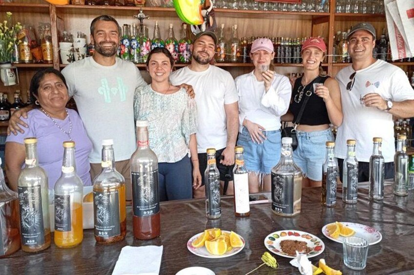 A group of people standing at a bar with various bottles and plates of food. 2