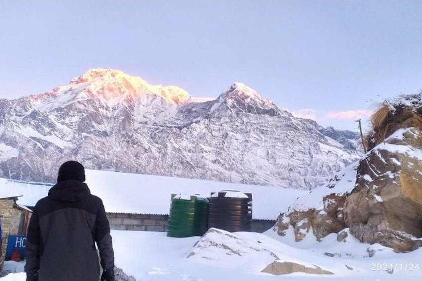 Eine Person steht in einer verschneiten Landschaft, im Hintergrund sind Berge zu sehen. 2
