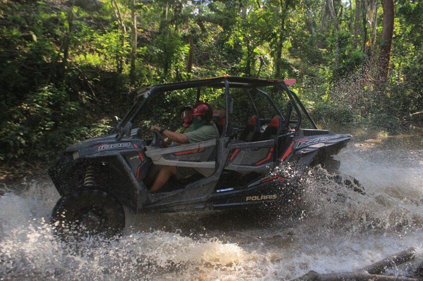 A Polaris ATV driving through a water body surrounded by dense greenery. 3
