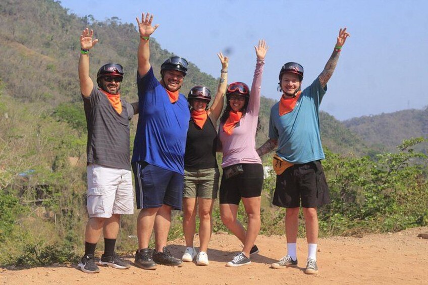 A group of people on a dirt path with trees and hills in the background. 5