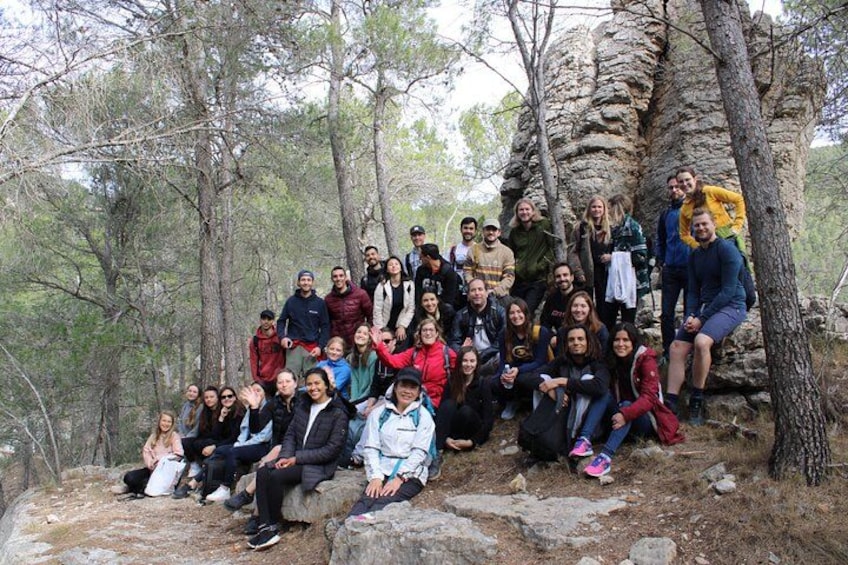 A group of people posing in a forested area with trees and rocky terrain. 3