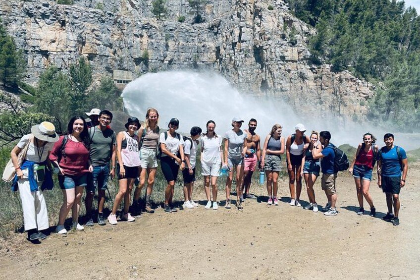 A group of people standing on a dirt path with a rocky cliff in the background. 1