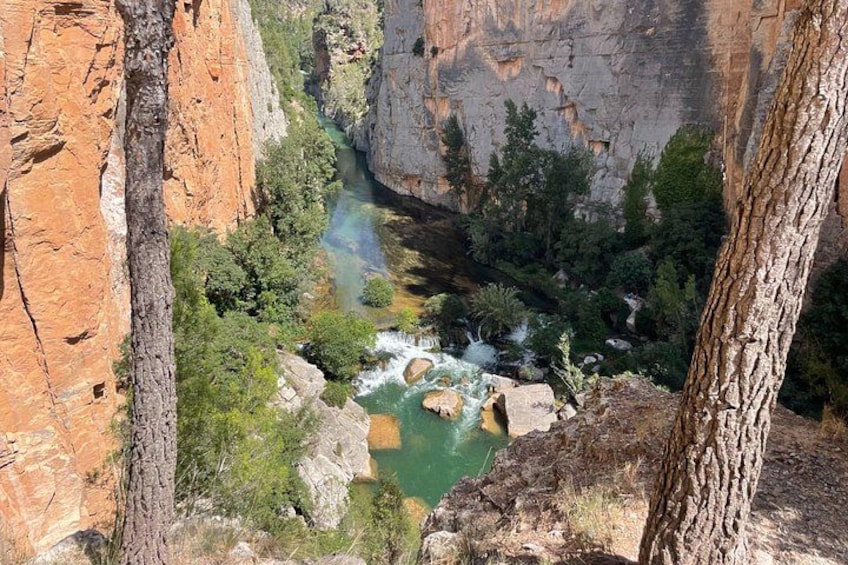 A canyon with a river, rocky cliffs, and trees. 3