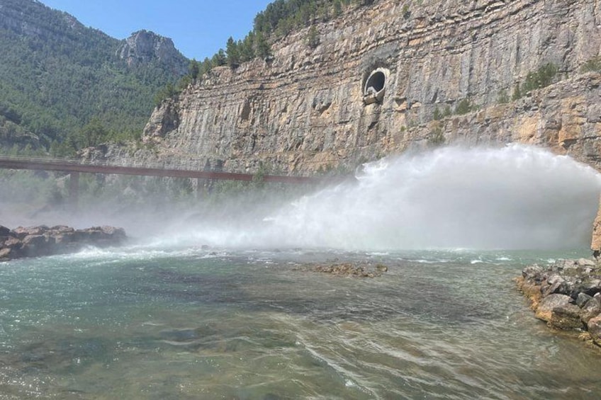 A river with a waterfall, rocky cliffs, and a bridge. 2