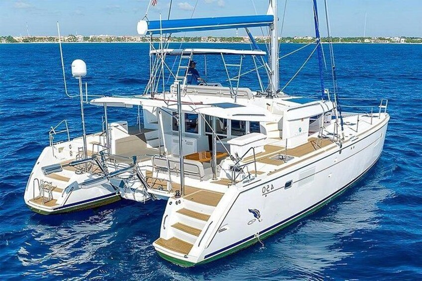 A white yacht with a blue canopy and a green stripe, floating on blue water. 2