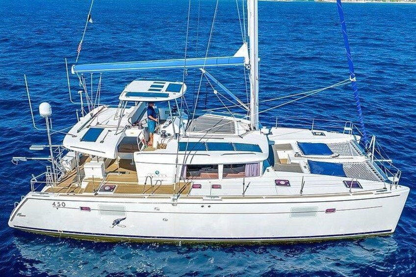 A white sailboat with a cabin, deck, and a person standing on the deck. 4
