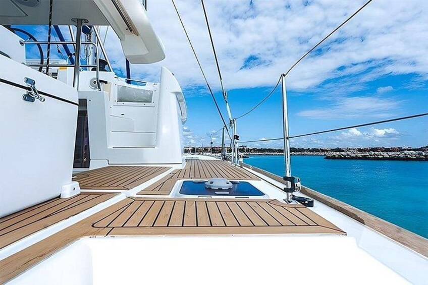 A yacht deck with a wooden floor, a small pool, and a view of the water and distant shoreline. 5