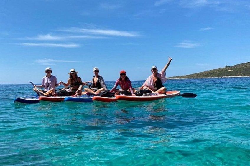 A group of people on paddleboards in clear blue water. 4