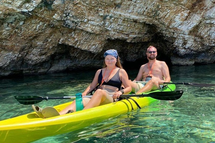 Two people kayaking in a yellow kayak with a rocky cave in the background. 5