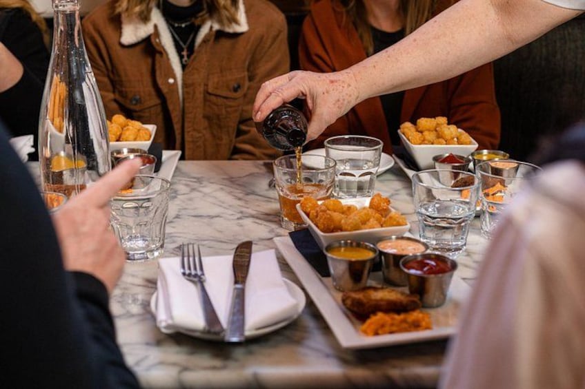 A dining table with food, drinks, and a bottle. 1