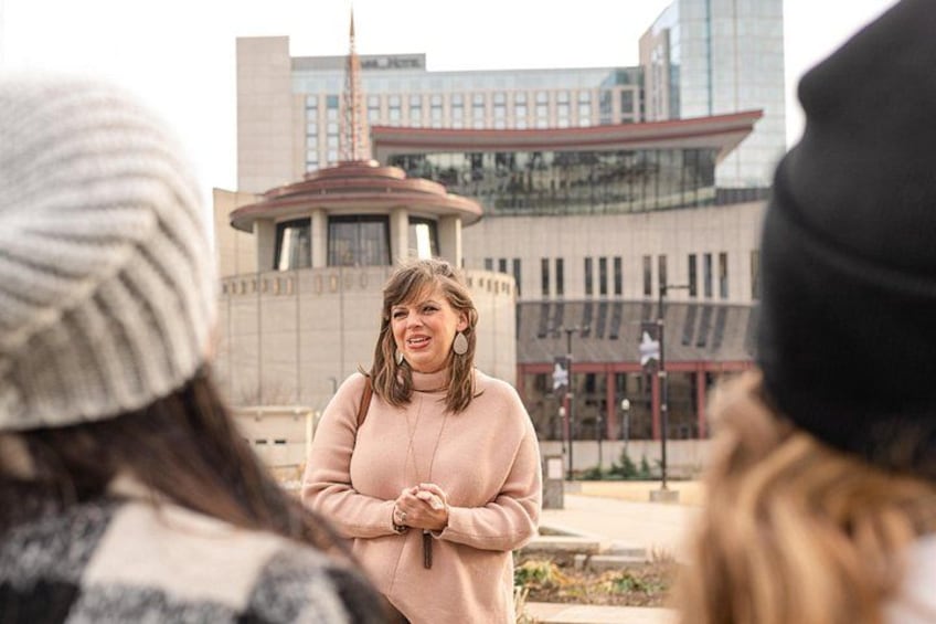 A person standing outdoors with a modern building in the background. 3