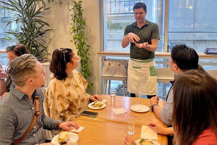A restaurant setting with diners, a waiter, and a table with food and drinks. 3